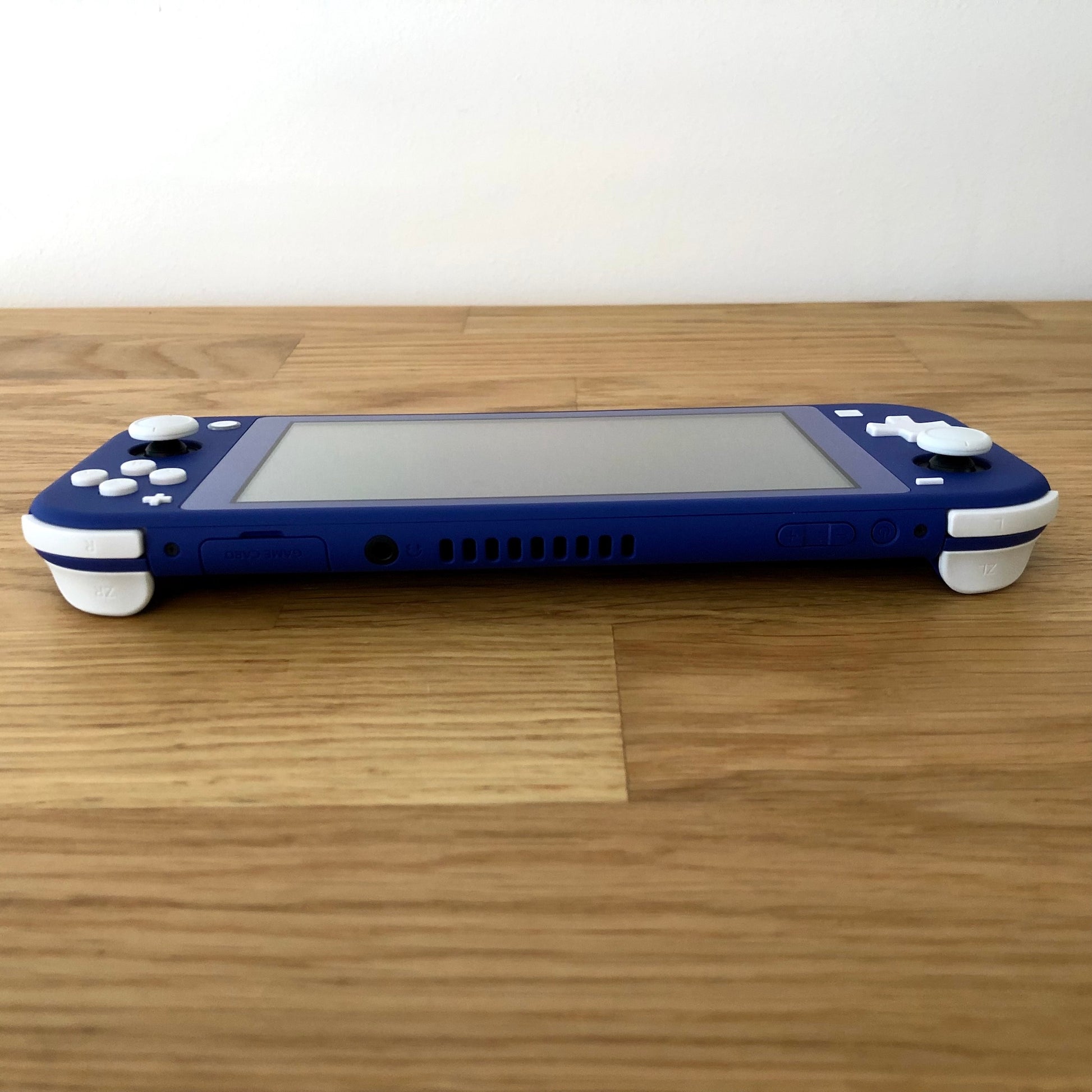 Back of Nintendo Switch Lite in blue, laid flat with white trigger buttons and Nintendo Switch logo visible.