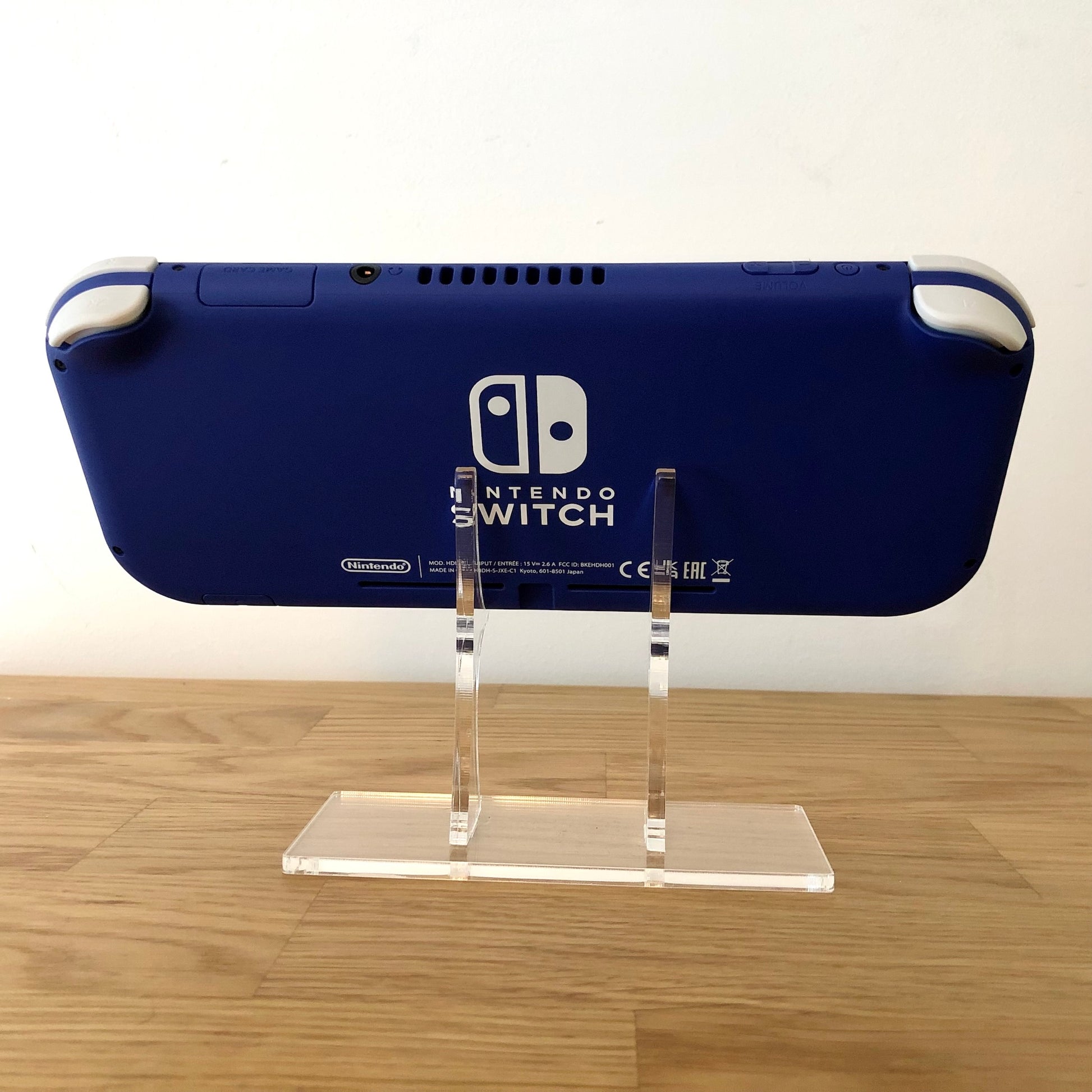 Rear view of blue Nintendo Switch Lite console on stand, showing Nintendo Switch branding and condition.
