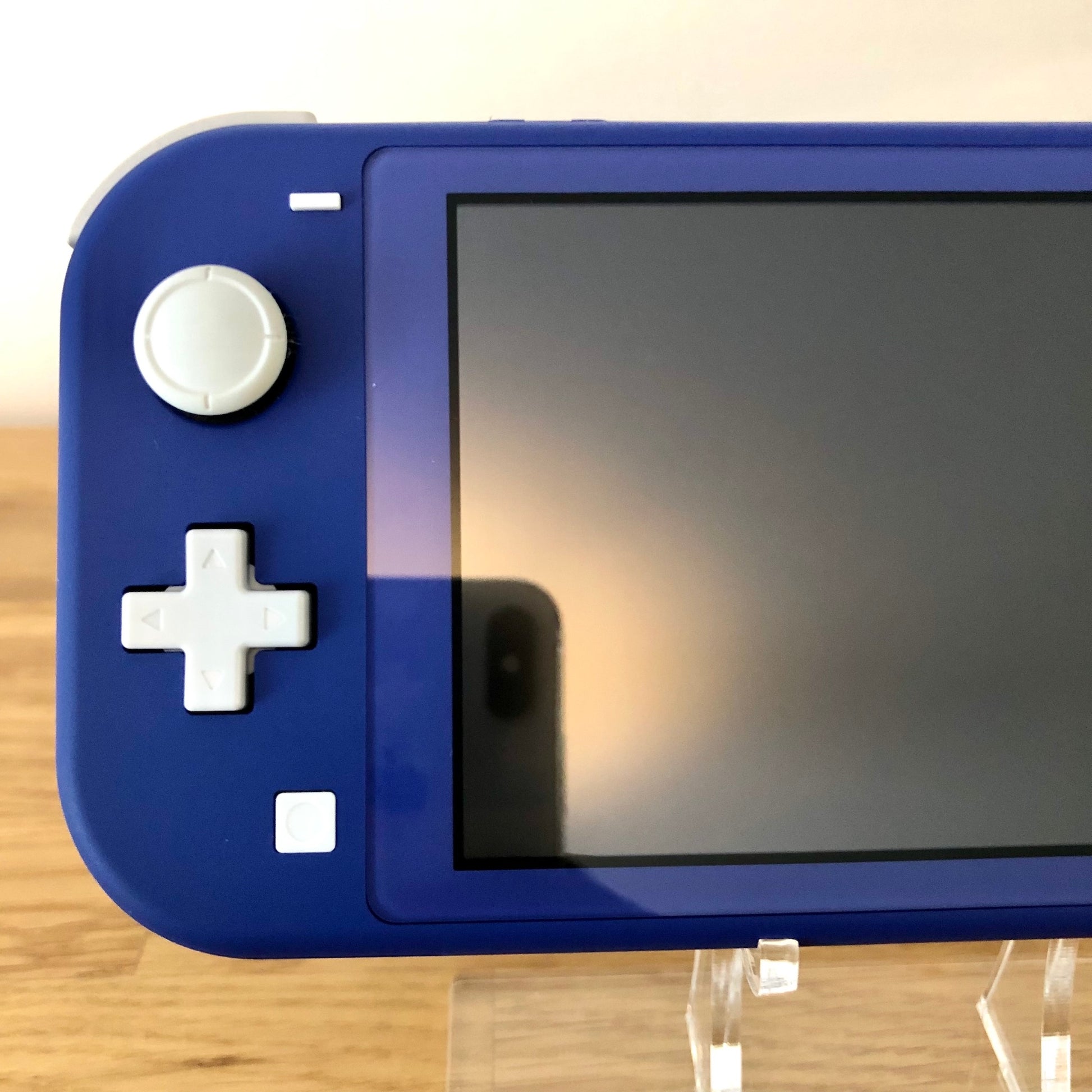 Close-up of left side of blue Nintendo Switch Lite showing joystick, D-pad, and capture button.