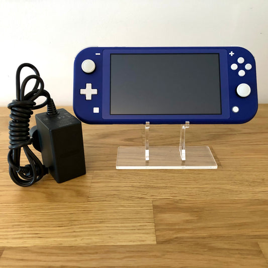 Front of Nintendo Switch Lite in blue, displayed on a stand with official charger placed beside it on a wooden surface.