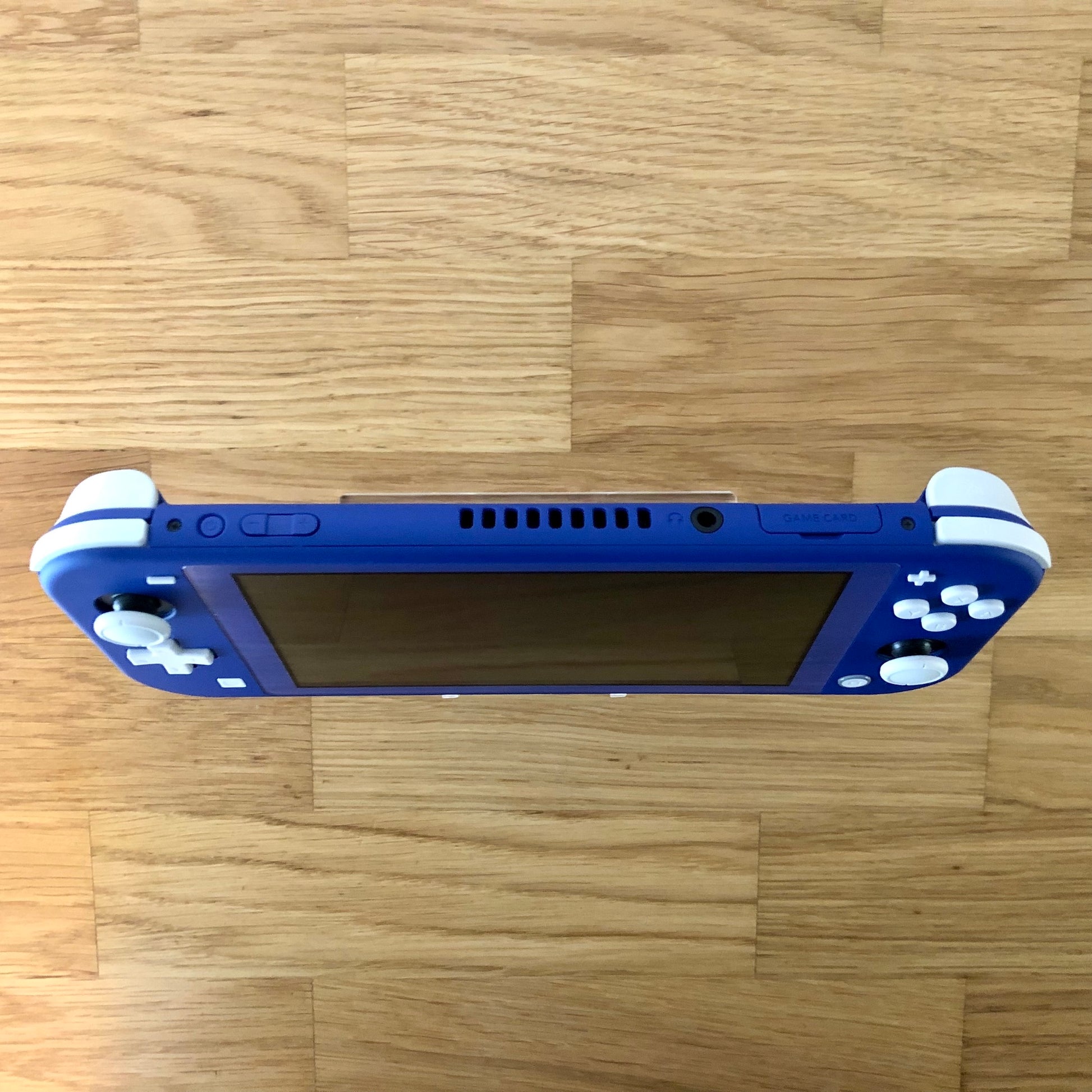 Top view of blue Nintendo Switch Lite console showing volume, power, headphone jack and game card slot.