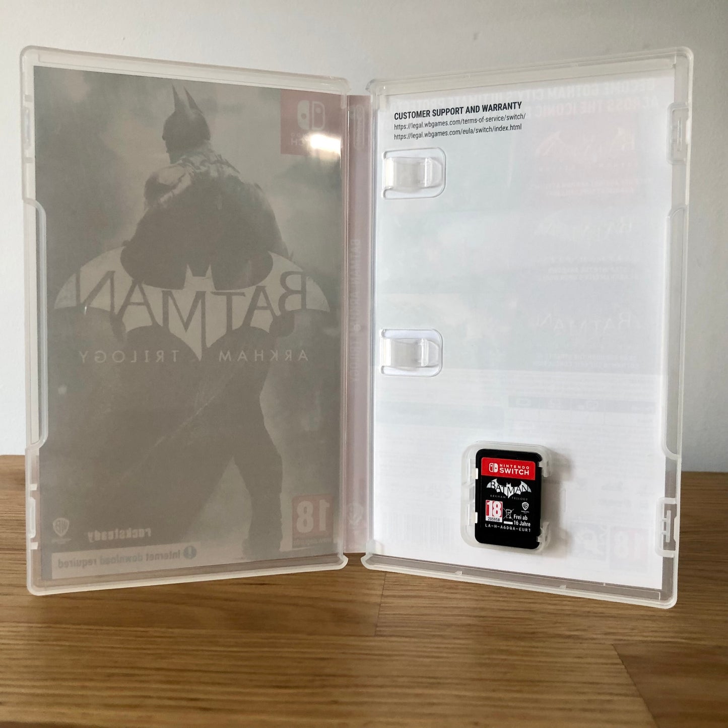 Inside the case of Batman Arkham Trilogy for Nintendo Switch, showing artwork and cartridge in slot